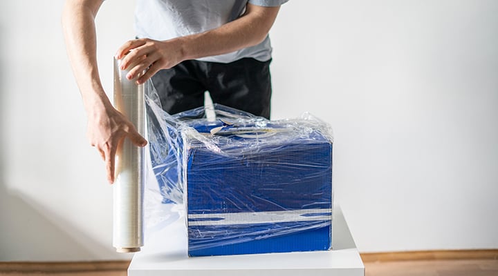 packing hack man uses plastic wrap to keep moving box items secure